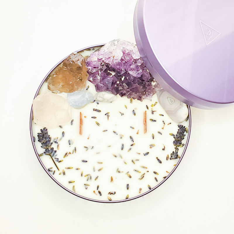 Crystal Candle in purple container with two wood wicks, Amethyst cluster, Clear Quartz point, Botswana Agate, Smoky Quartz, Howlite, Blue Calcite, and Organic Lavender.